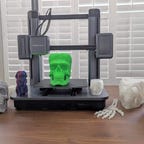AnkerMake M5 3D printer on a table with a selection of printed skulls