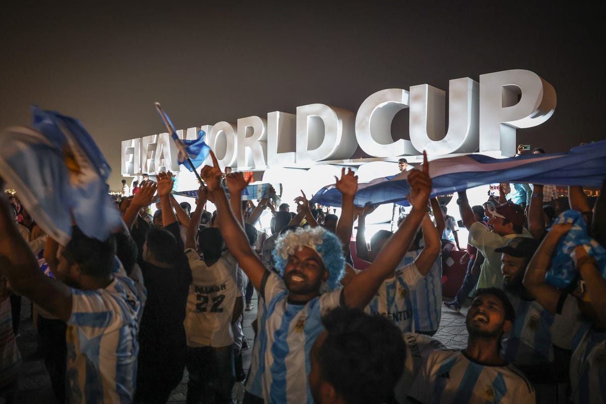 Fans with blue hair and jerseys celebrate in Qatar for the World Cup.