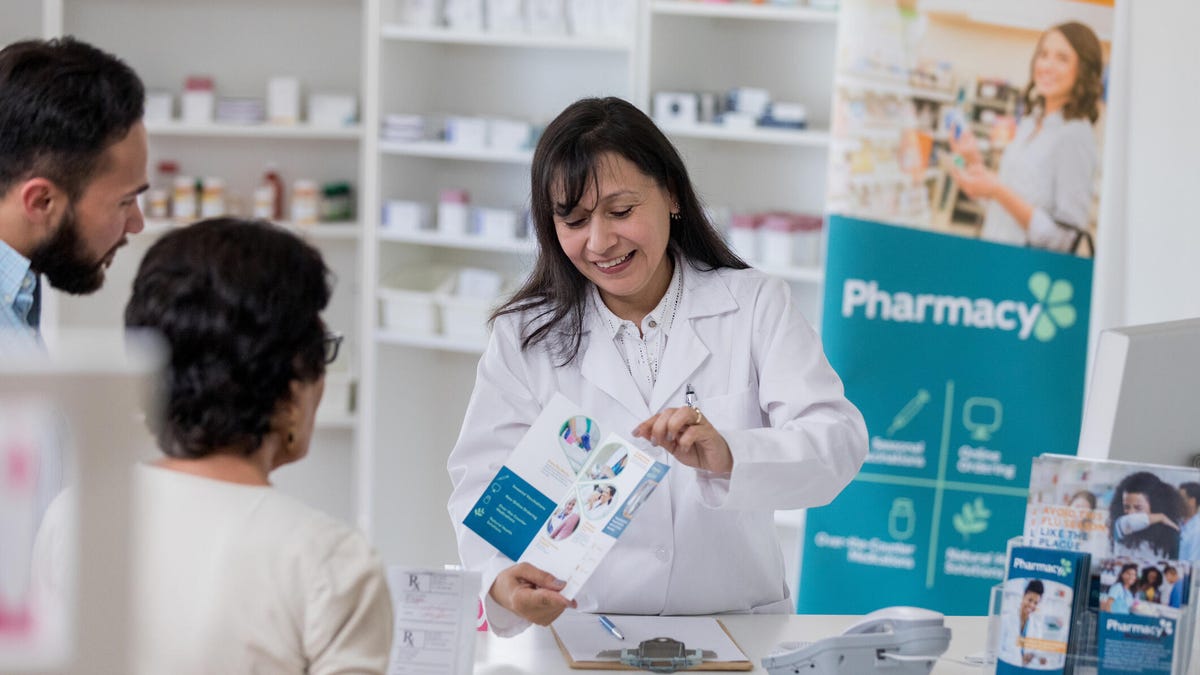 Pharmacist giving brochure to mother and son