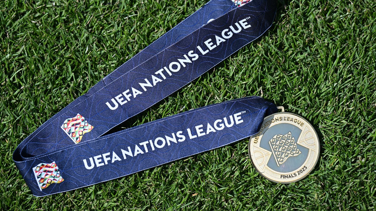 A Nations League 2023 winners medal laying on grass.