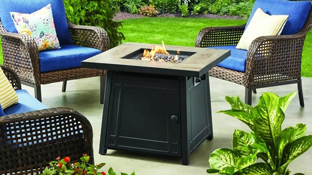 A Mainstays 30-inch Outdoor Gas Fire Pit Table sits on an outdoor patio.