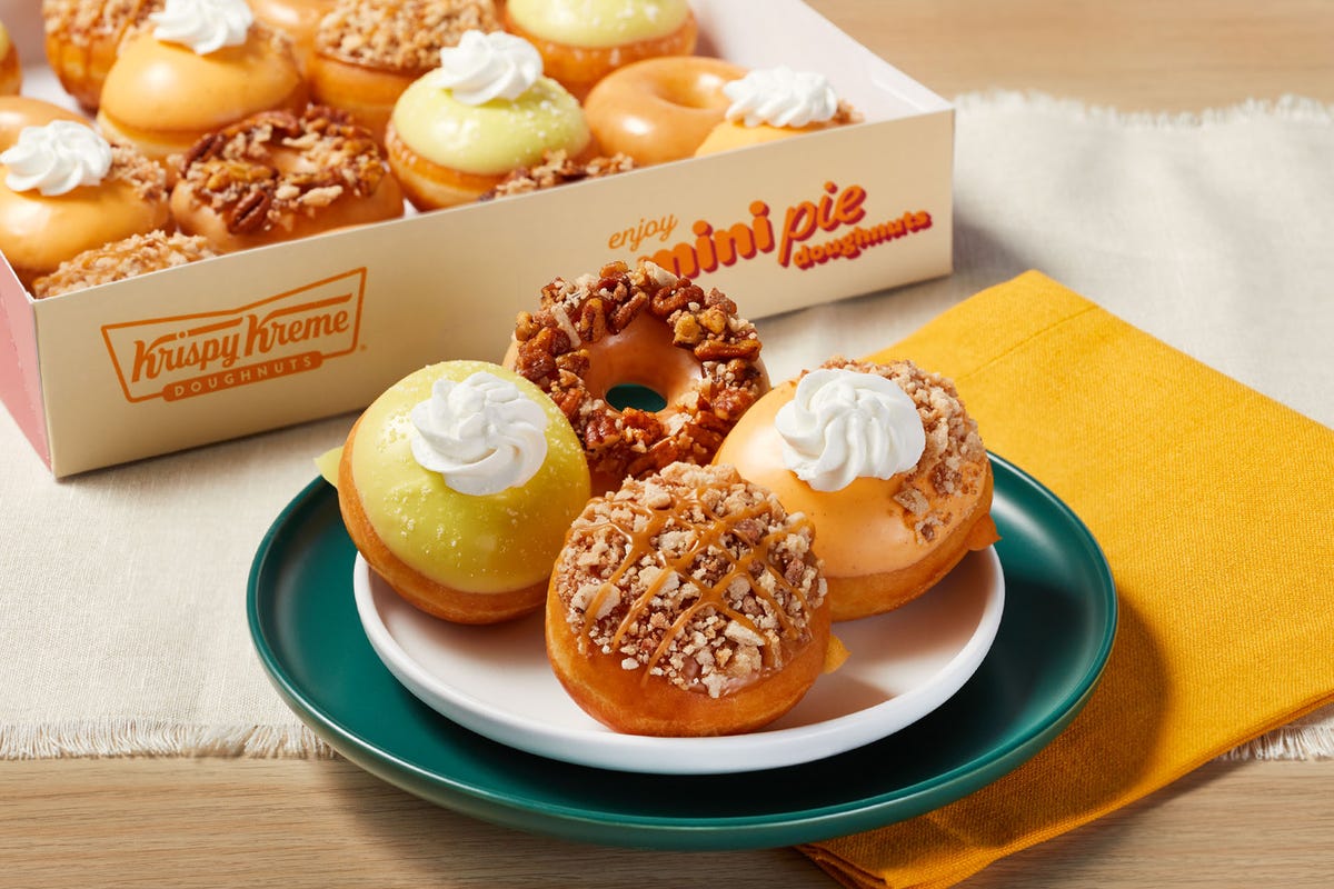 Four doughnuts on a plate in front of a box of doughnuts