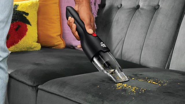 Person cleaning up crumbs on a couch with the vacuum