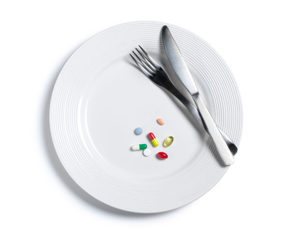 A plate with several pills and supplements instead of food.