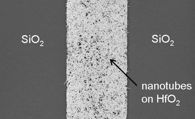 IBM's silicon wafers have two surfaces on top, hafnium oxide and silicon dioxide. This close-up image shows speckles of carbon nanotubes that bond only with the hafnium oxide, part of IBM's approach to positioning them precisely on a chip.