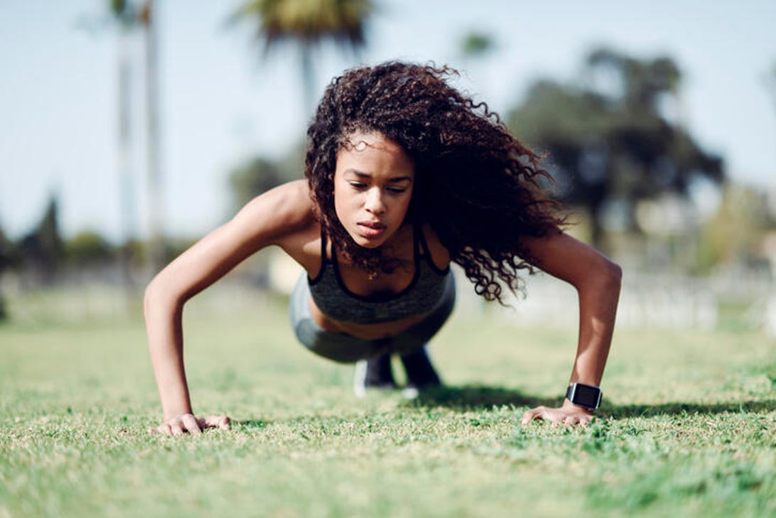 young woman doing a push up on grass