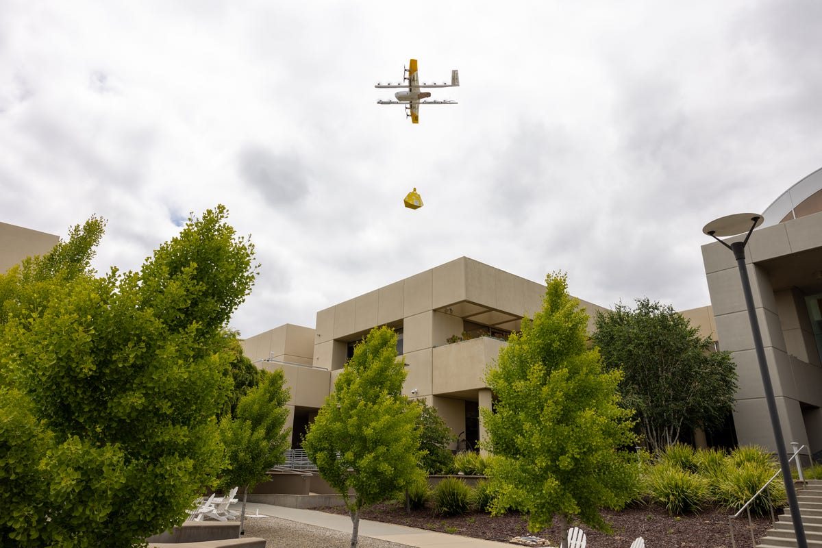 A Wing delivery drone delivers its package by lowering it from about 22 feet up using a tether.