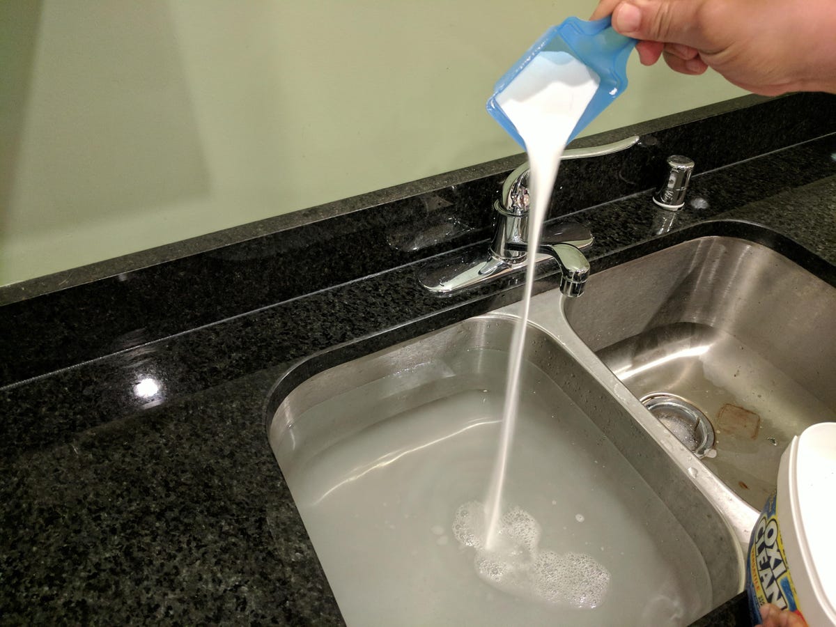 hand pouring baking soda into a kitchen sink