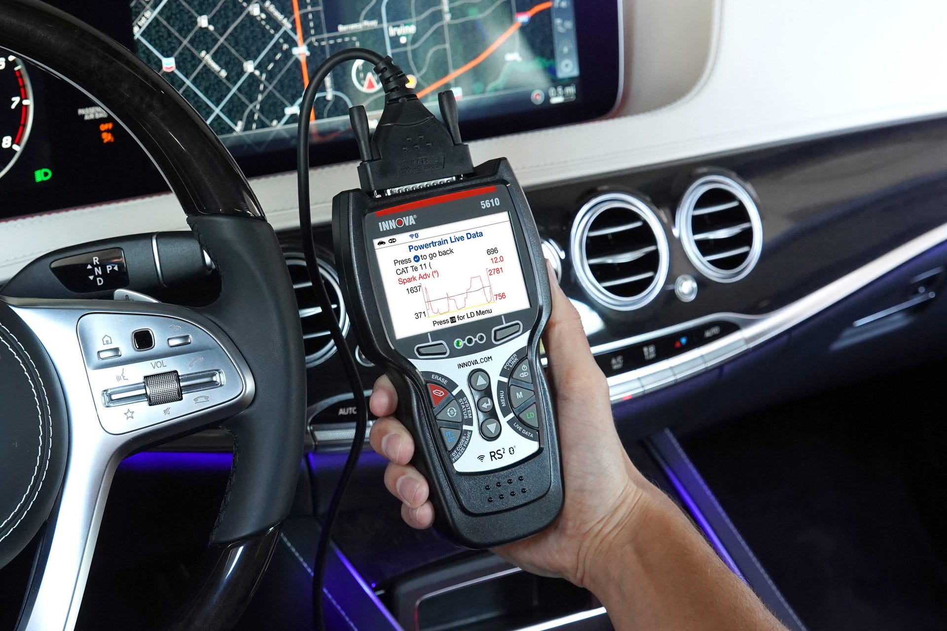 A hand holding up an OBD2 scanner.