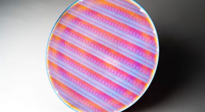 A circular silicon wafer studded with colorful chips
