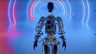 A skeletal-looking Tesla Bot in front of neon lights