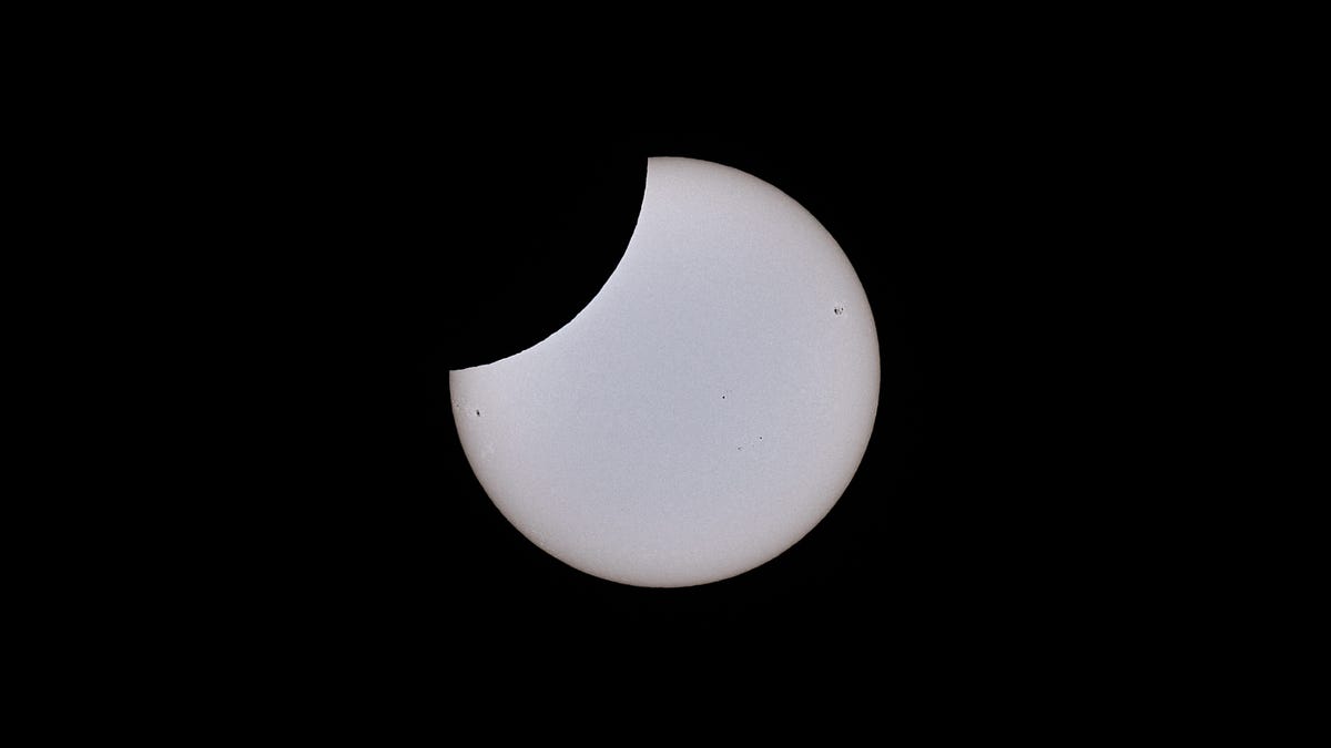 The sun appears in a telescope view as a light-colored circle with a dark rounded bite taken out.