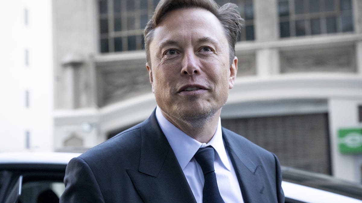 Elon Musk wearing a coat and tie.