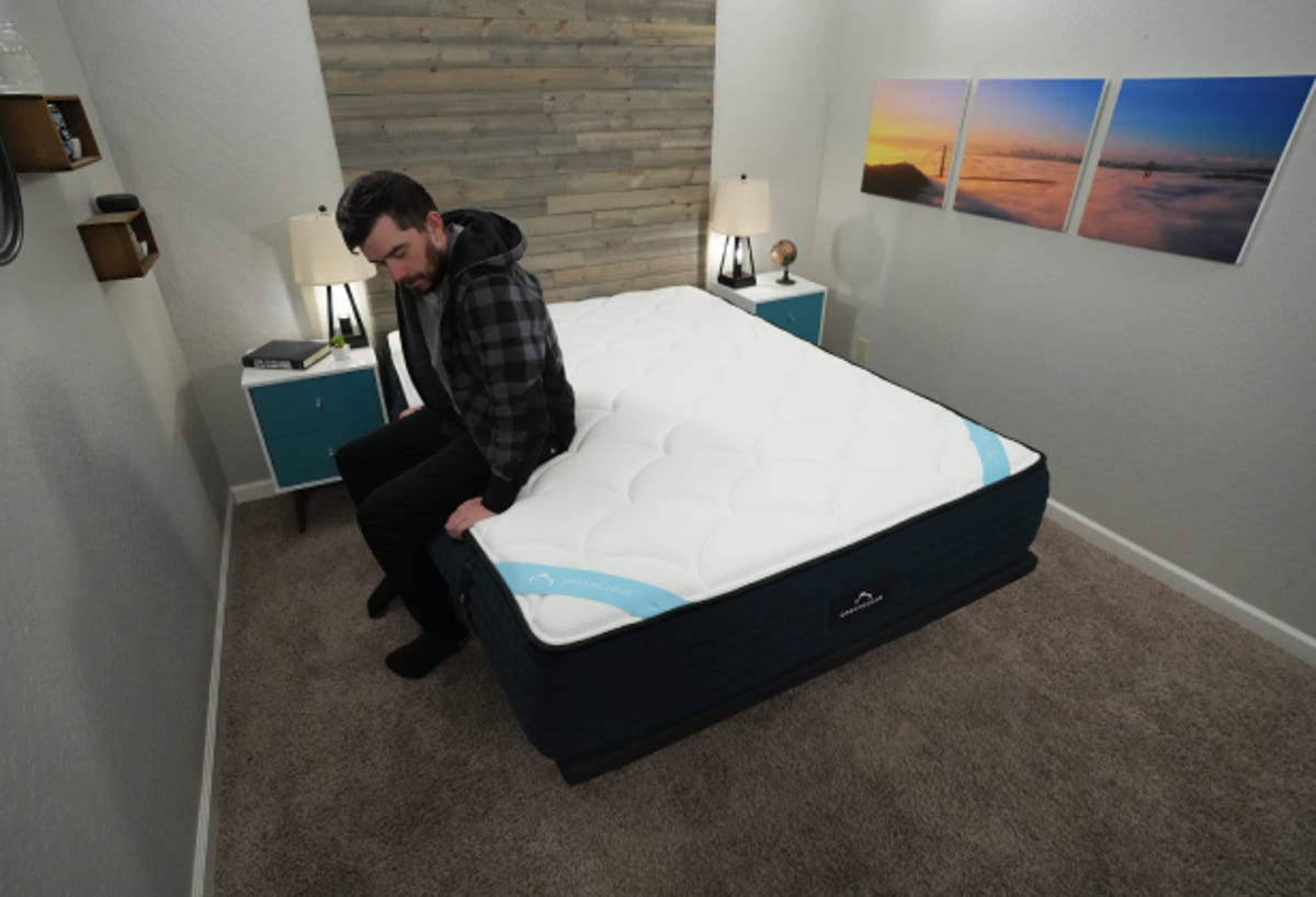 Owen sitting on DreamCloud Premier all-foam mattress
