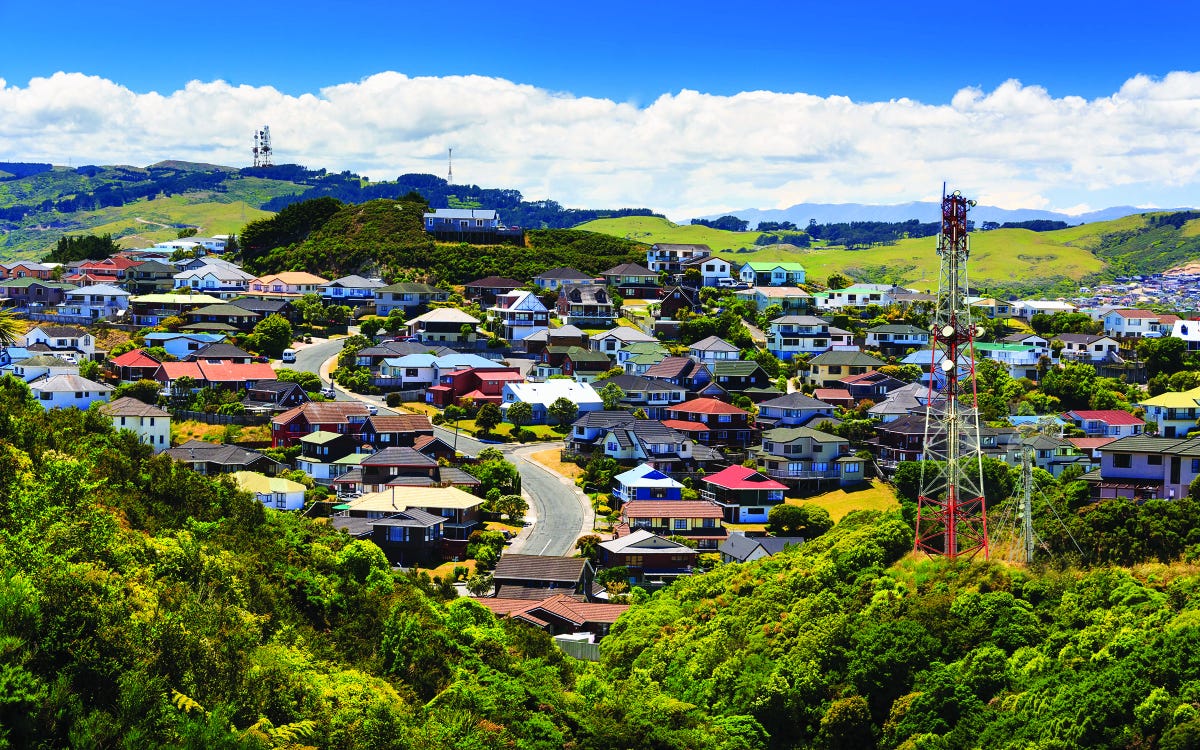 A wide view of a small town nestled among hills with an antenna in the foreground.