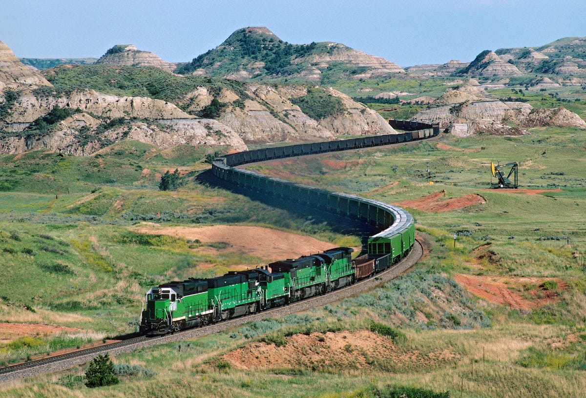 A freight train heads west through the scenic Badlands of North Dakota at Sully Springs on a summer afternoon.