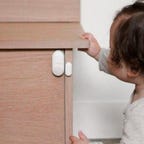 A toddler approaches an Ecobee sensor protecting a wood cabinet door.