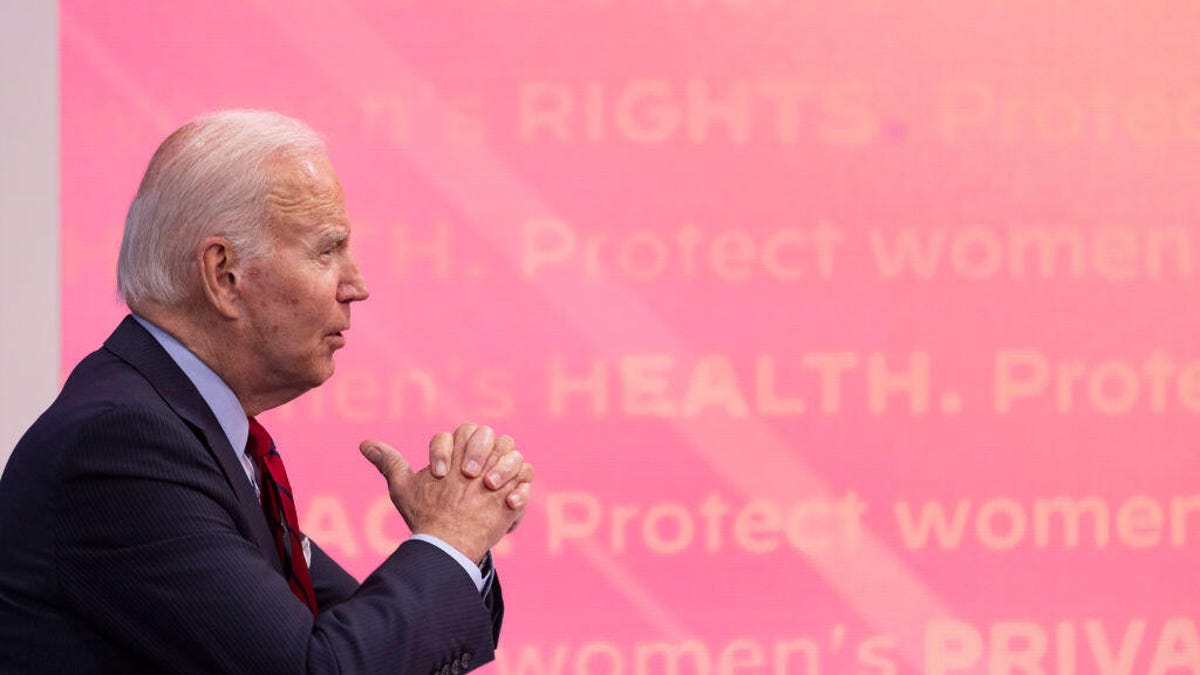 President Joe Biden is seen from his right, with pink reproductive rights panel in background to his left
