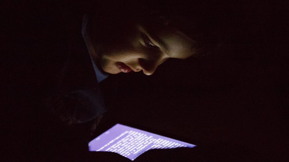 The author's son reading a dim e-book in a pitch-dark room, photographed at ISO 25,600.