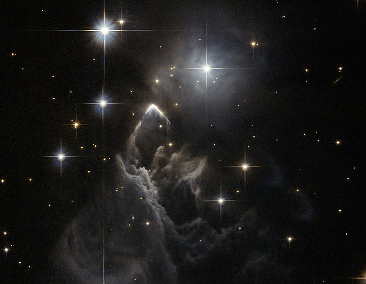 Magical nightmare space image with lots of gleaming stars and a gray collection of ghostly dust clouds forming into mounds.