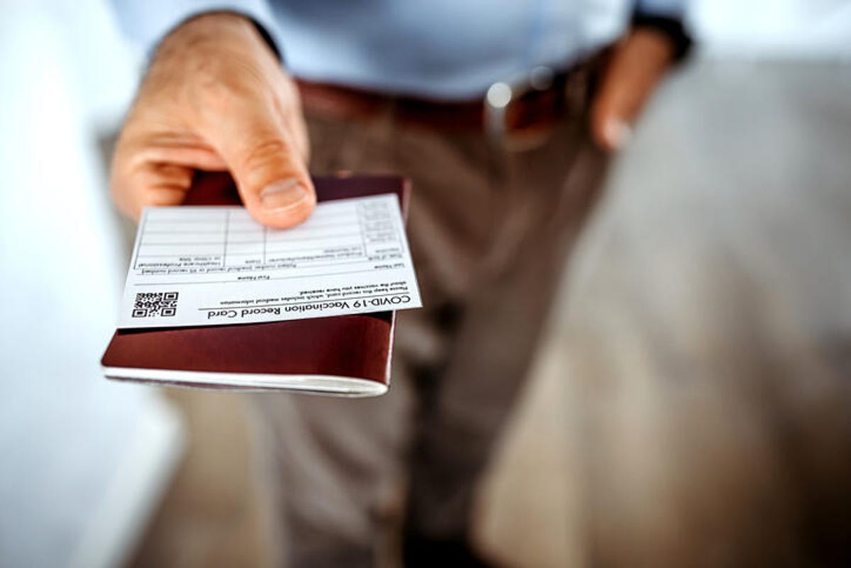Man holding vaccine card and passport