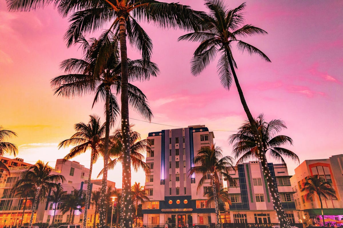 Photo of art deco Miami apartment blocks with palm trees and a pink sky