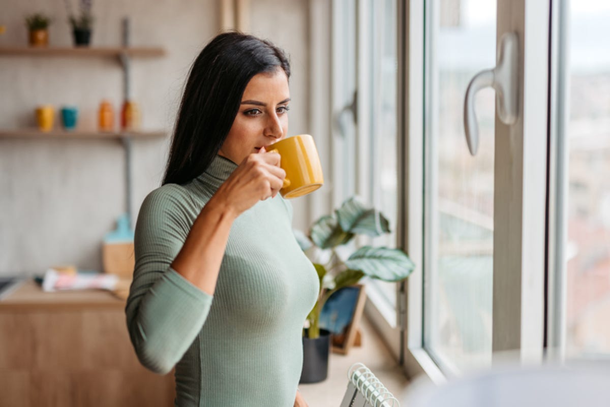 Woman drinking coffee while looking out of the window.