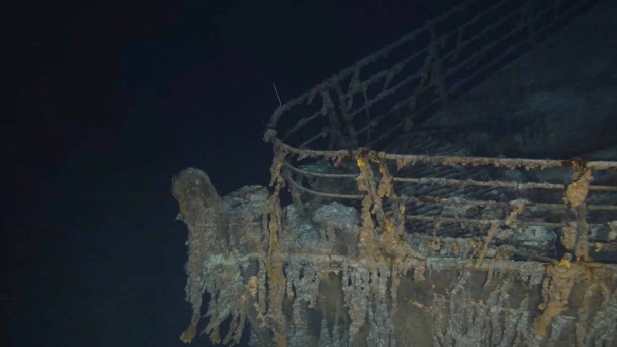 View of the Titanic's encrusted bow with railings underwater. Dark and moody.