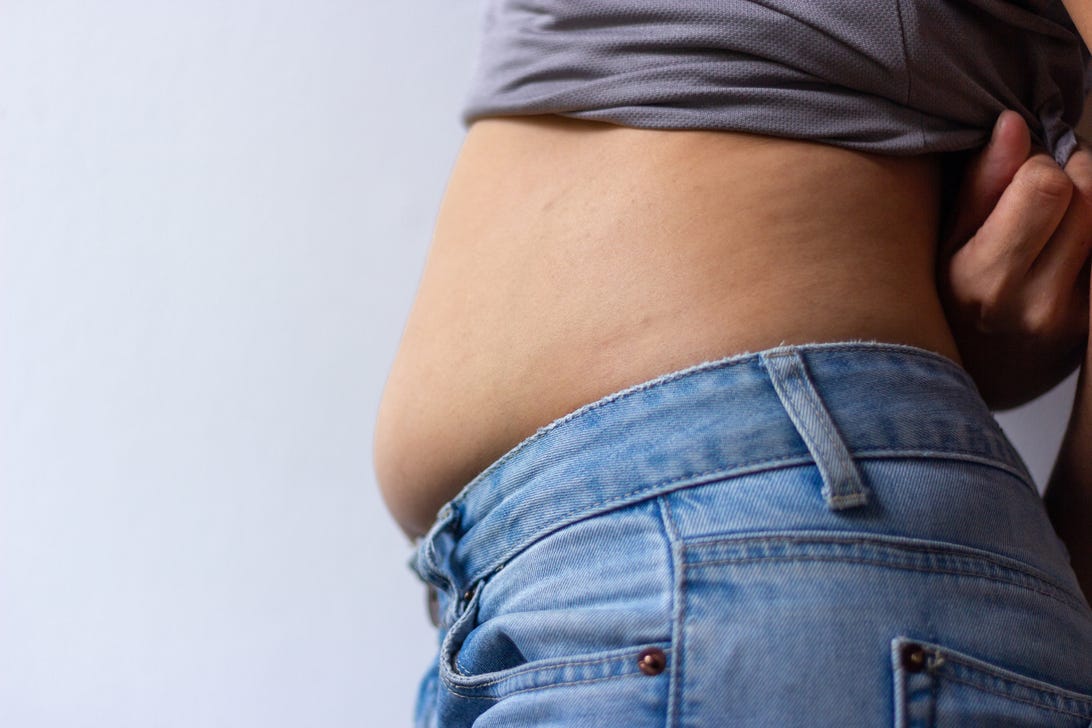 Woman's midsection in jeans, with slightly bloated belly