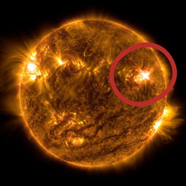 An orangey full disk view of the sun shows a bright flash on one side circled in red.