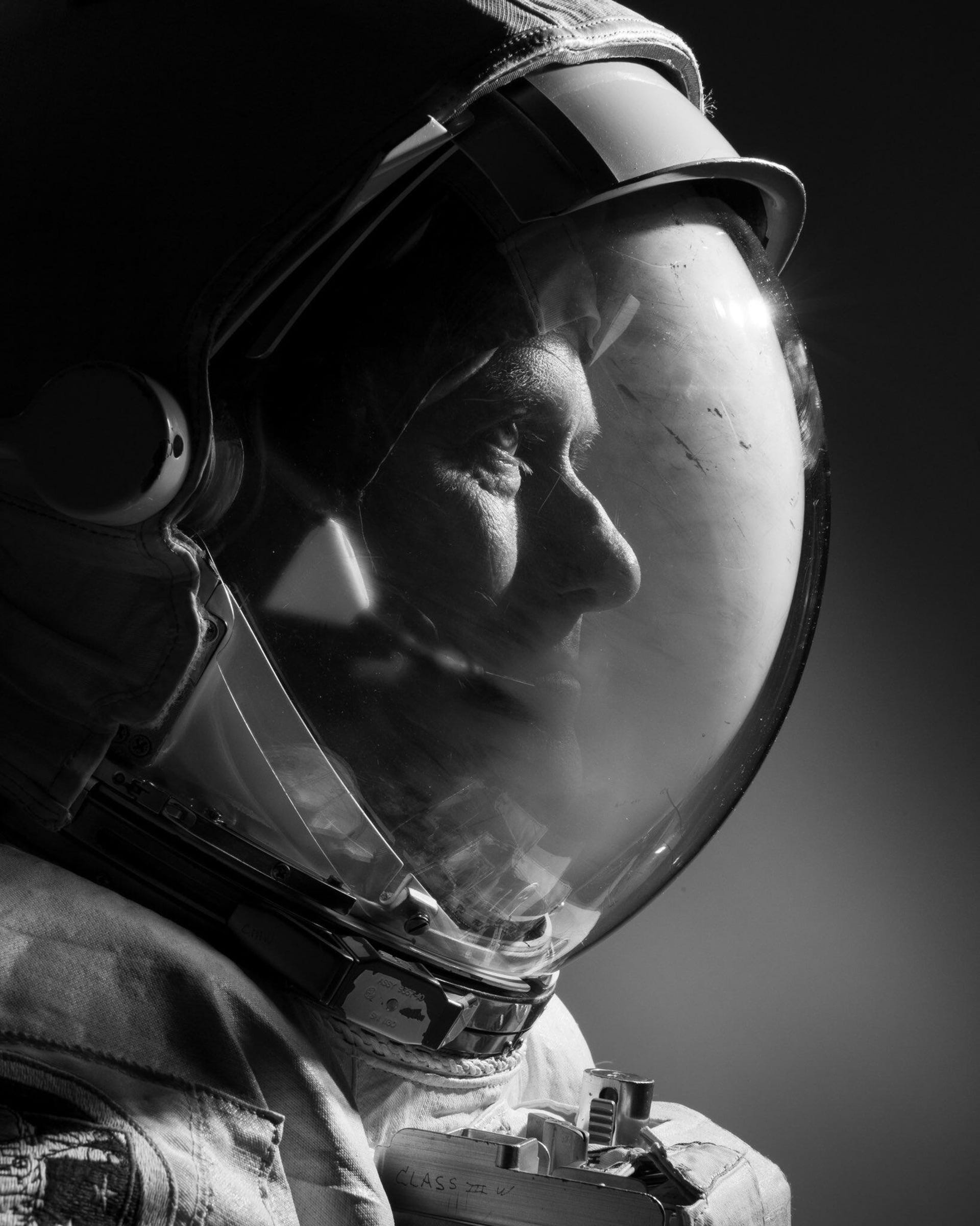 Sideways portrait of astronaut in a spacesuit with light shining through the helmet.