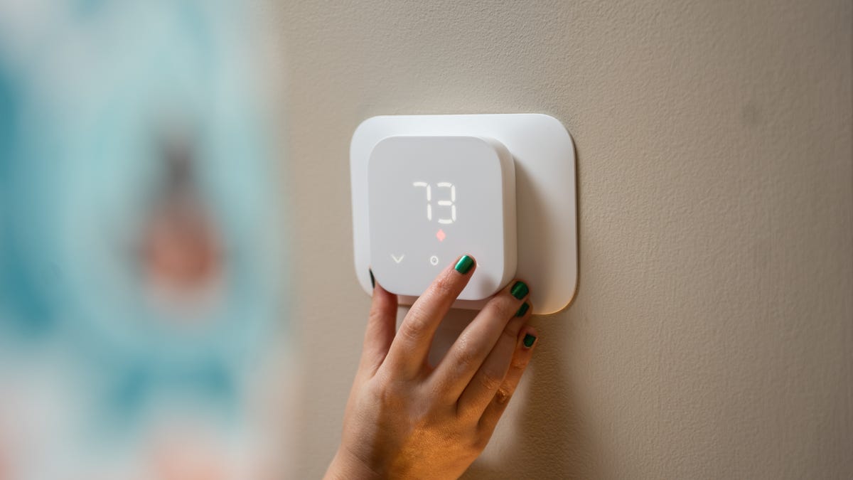 a hand on a thermostat reading 73 F