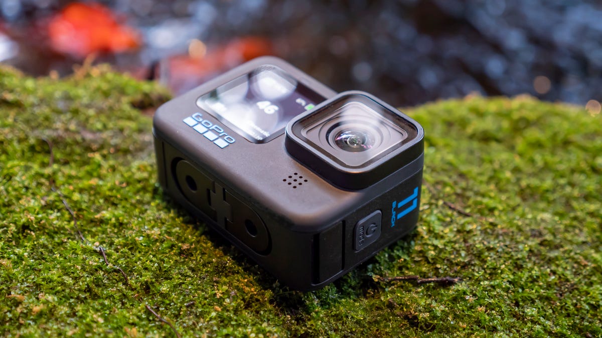 GoPro Hero 11 Black lying on its back pointing up on a bed of green moss. 