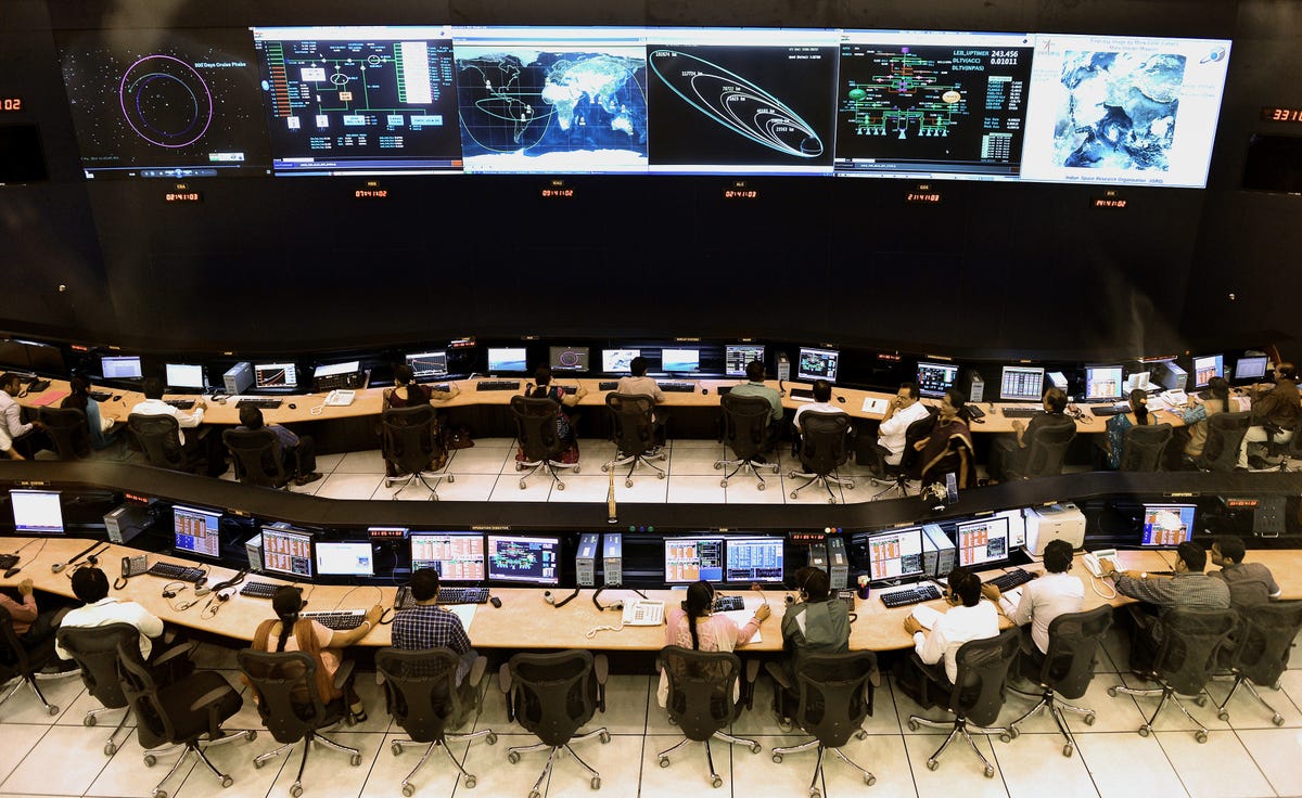 In a kind of theatre, scientists sit in rows of desks with computers.  The large monitors are at the front of the room, facing everyone.