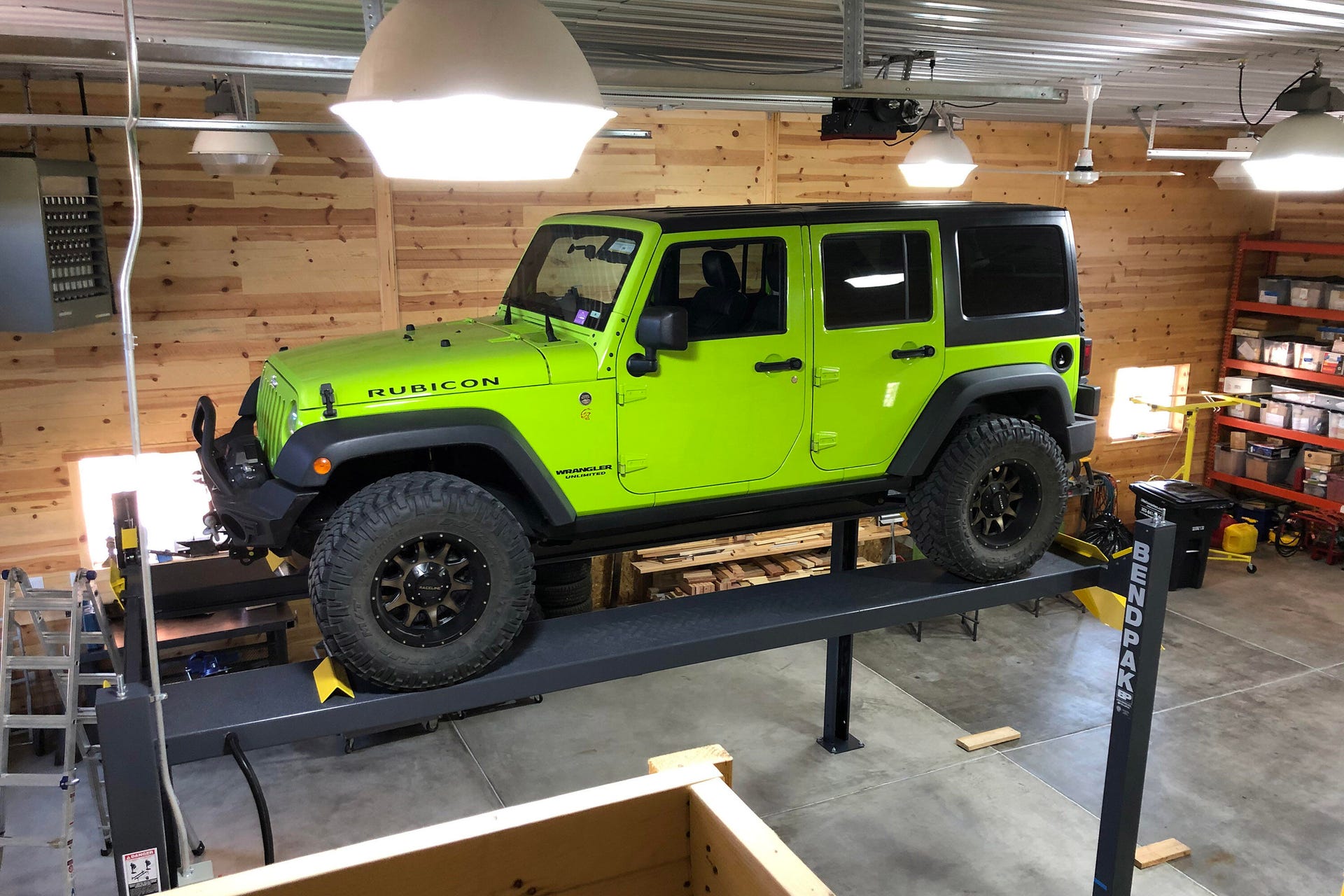 A green Jeep on a BendPak auto lift