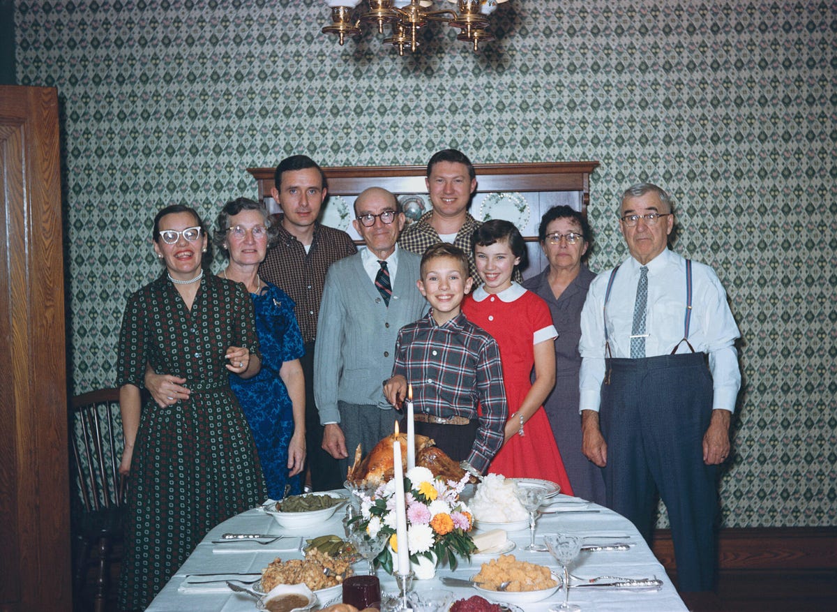 Nostalgic portrait of a multigenerational Caucasian family posing at Thanksgiving dinner.