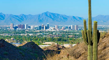 Phoenix skyline with mountains in the background and a saguaro cactus in the foreground.