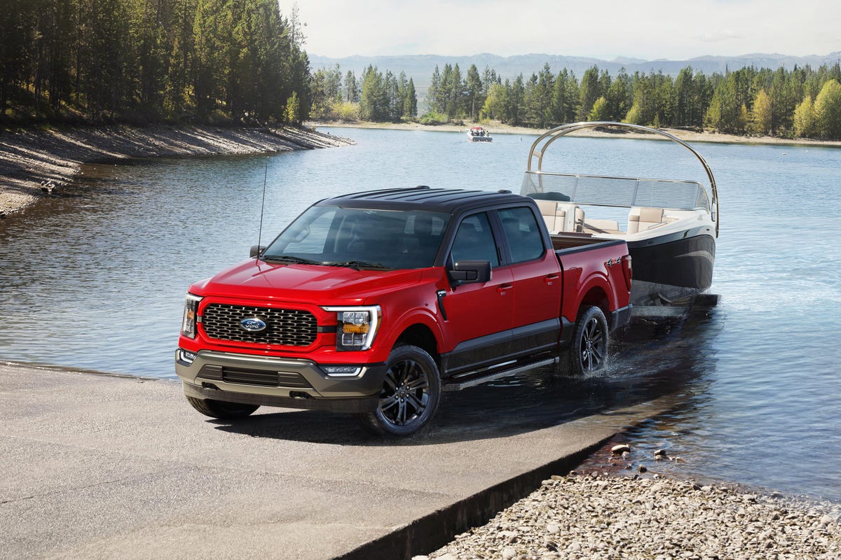A red 2023 Ford F-150 Heritage Edition towing a boat out of a dock