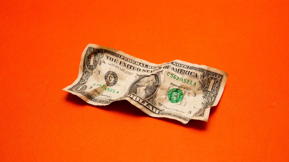 Crumpled US dollar bill on orange background