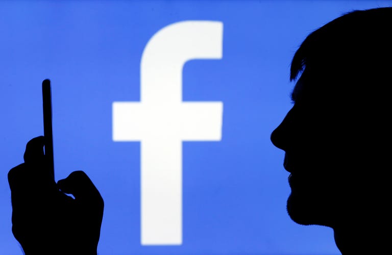 Facebook logo with silhouette of someone looking at a phone.