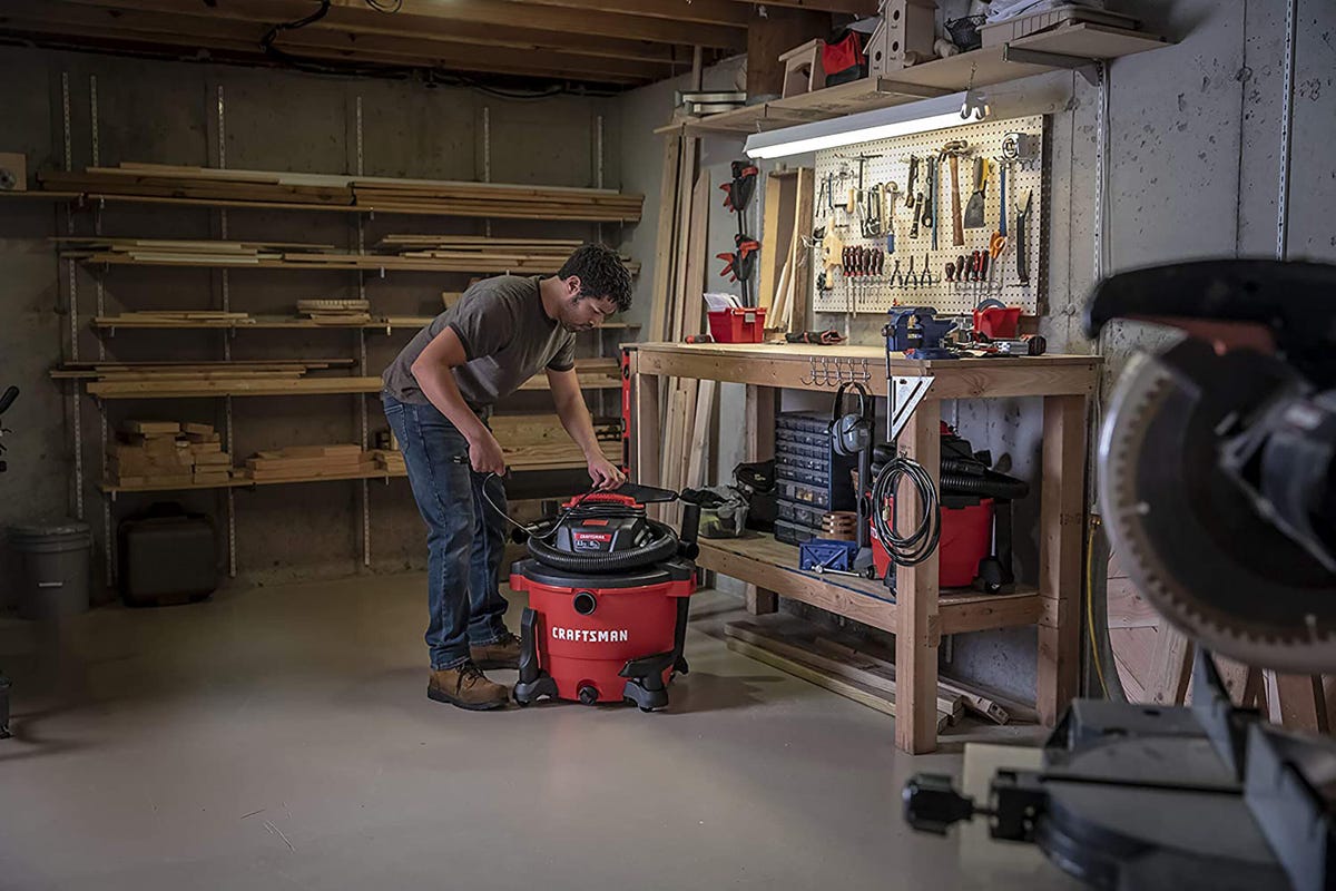 A man and a red Craftsman shop vac in a garage.