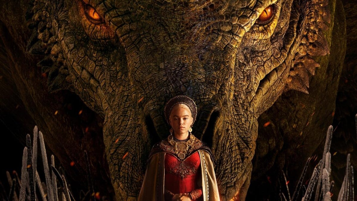 Rhaenyra Targaryen dressed in a red gown, stands in front of a dragon