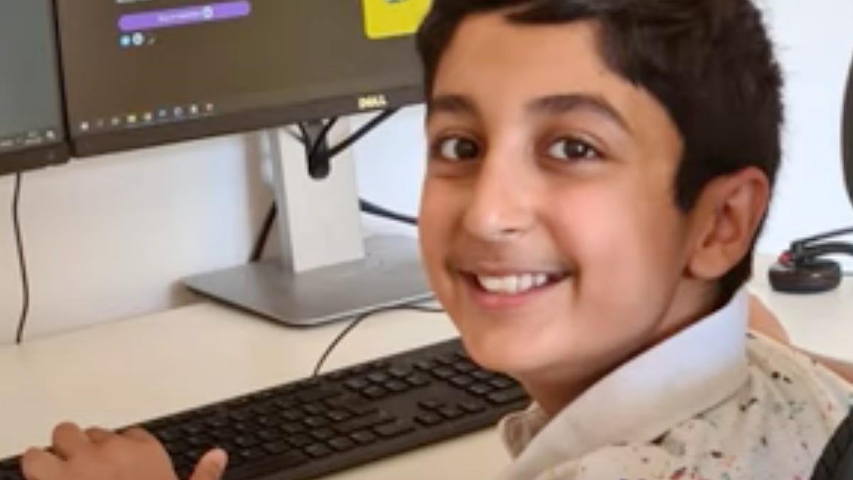 Benyamin Ahmed sits at a computer with Weird Whales on it