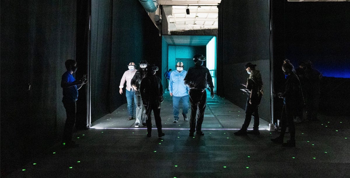 People in headset step into a dark open space dotted with green lights