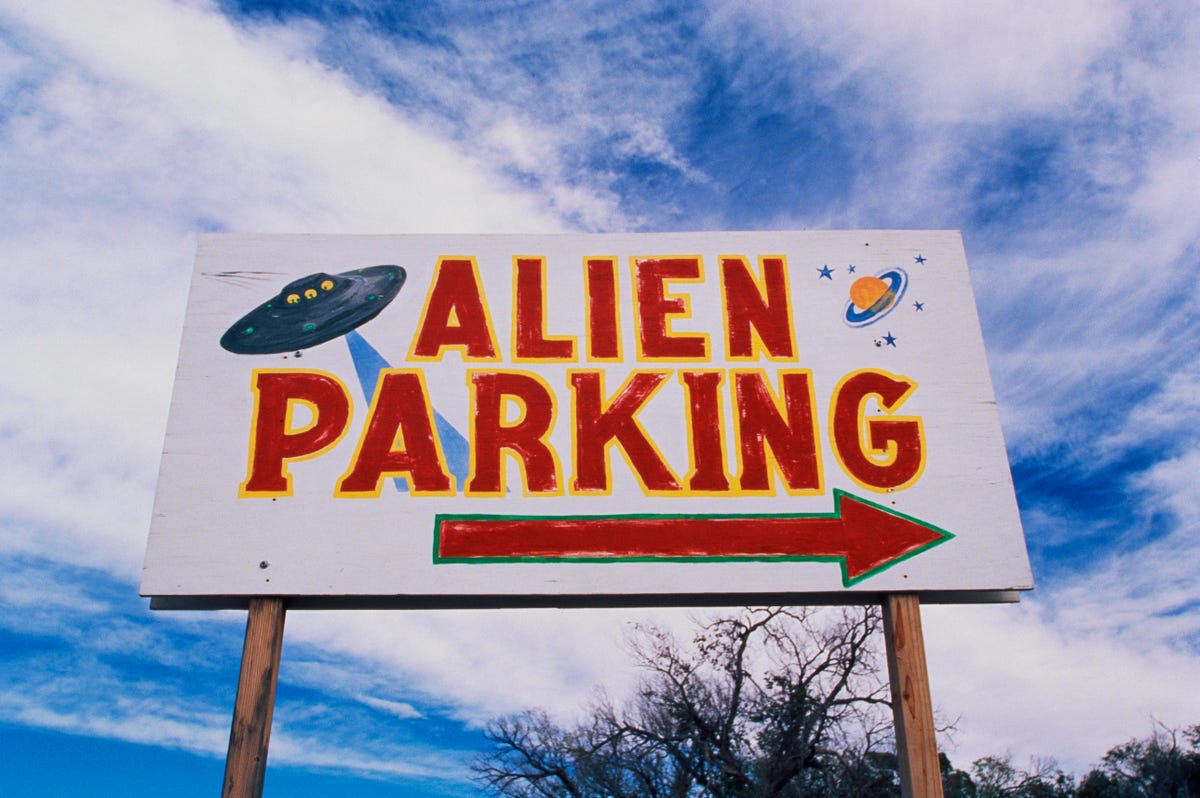 This is a road sign indicating where Alien Parking is. This is the original UFO crash site in Roswell. There are small UFOs on the sign with a large arrow pointing to the right.