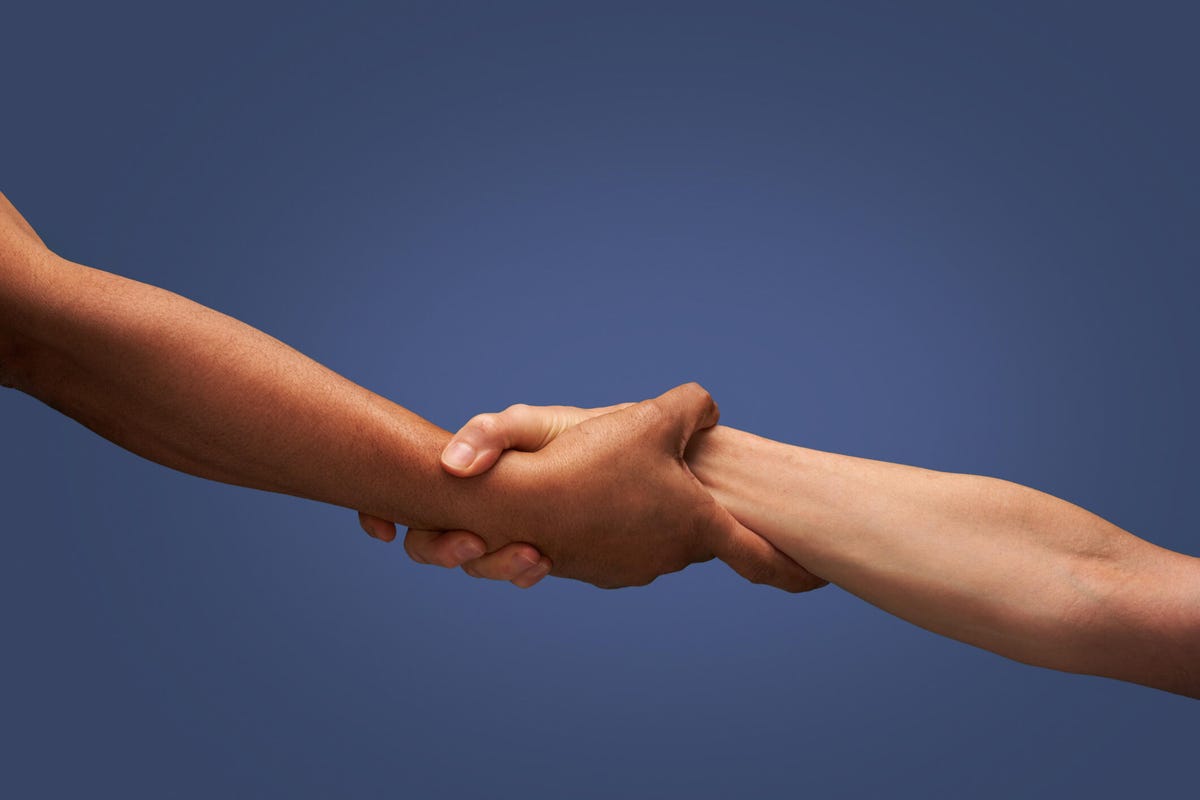 Two people grab each other's wrists against a dark blue background