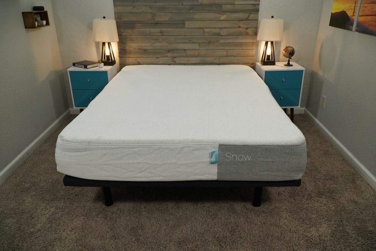 The Casper Snow mattress without any sheets or blankets inside a brightly lit room.