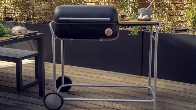 A Spark grill rests on a patio outside near a table.