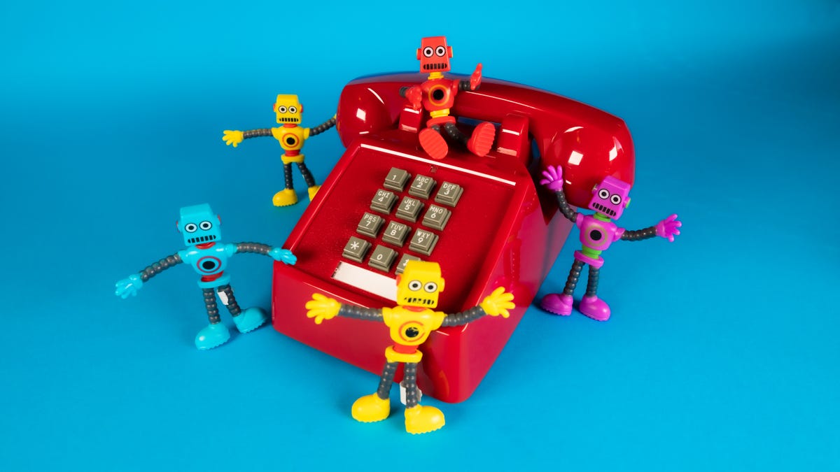 Five tiny robots around a red phone
