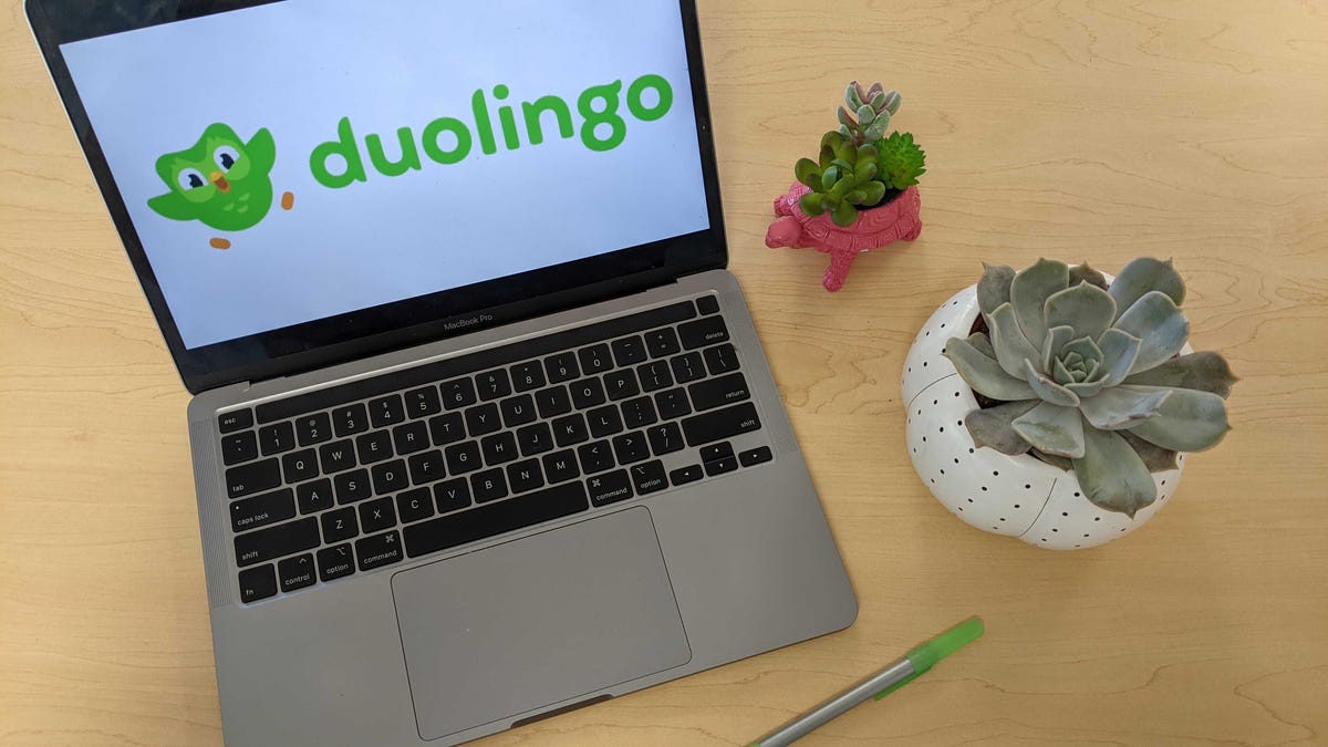 A laptop open on a desk with the Duolingo logo on the screen